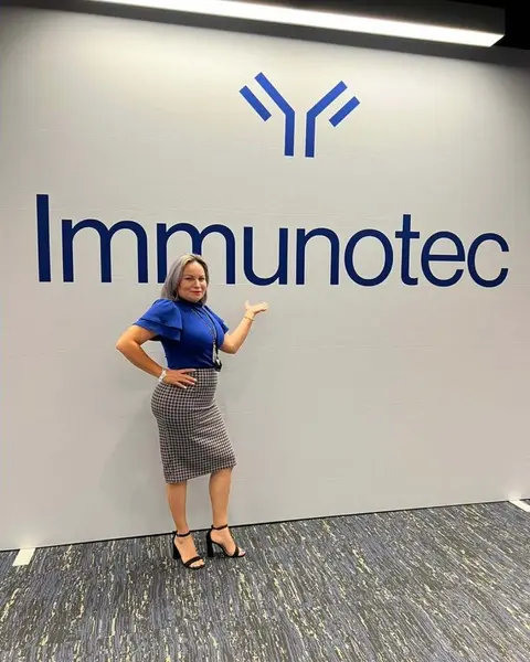 Carina de pie frente al letrero de Immunotec en las oficinas